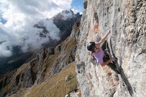 Eine Frau klettert eine Felswand hoch.