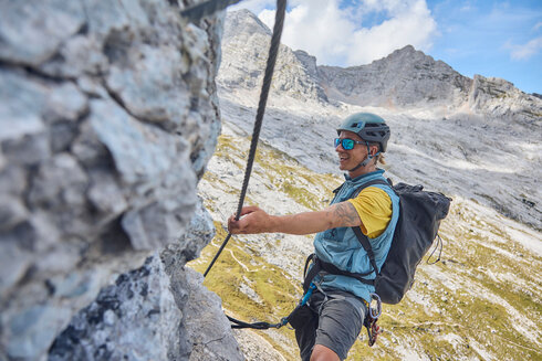 Ein Mann klettert einen Kettersteig in den Bergen