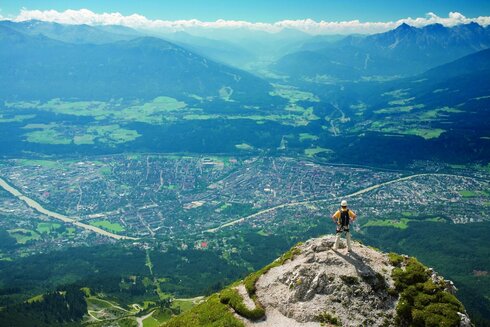 Der Klettersteiggeher steht am Gipfel und genießt die Aussicht auf Innsbruck. 