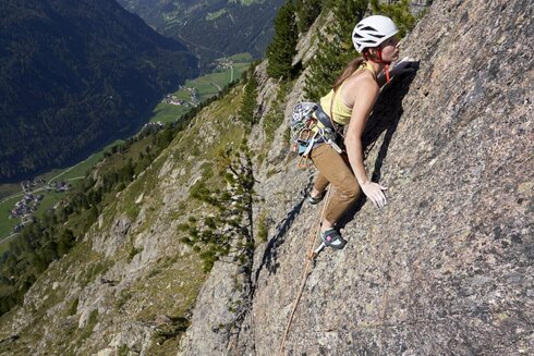 Eine Frau klettert die erste Seillänge einer Mehrseillängentour