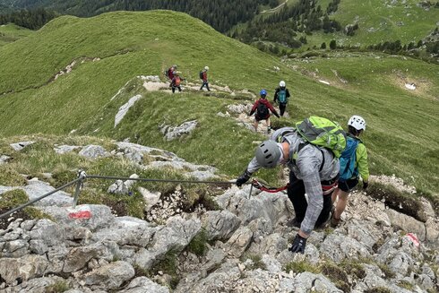 Eine Klettergruppe geht gesichert an einem Klettersteig