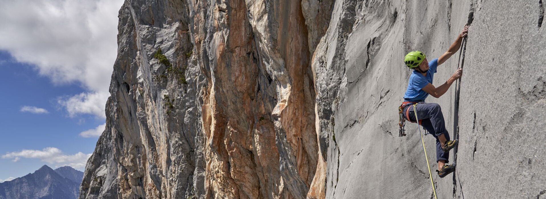 Ein Mann klettert mit einem Seil auf einem Felsen.