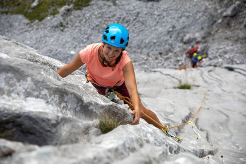 Eine Frau klettert einem Riss entlang. Der Kletterpartner sichert am Wandfuß seine Partnerin