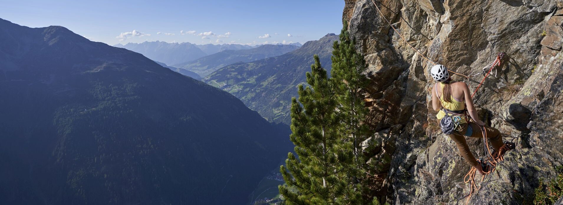 Zwei Personen klettern mit Ausrüstung auf einen Berg.